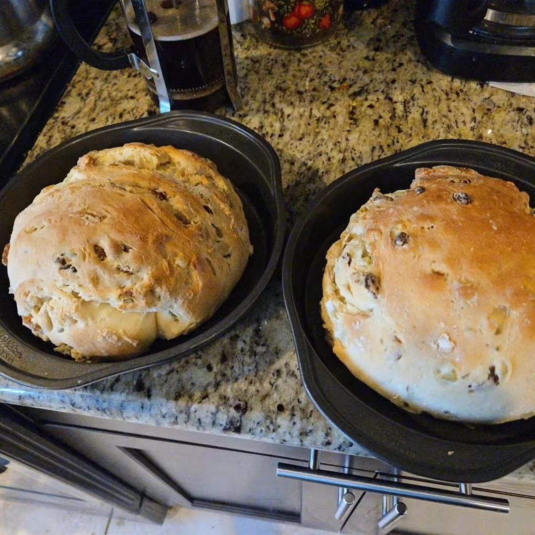 Two golden rustic loaves in baking pans