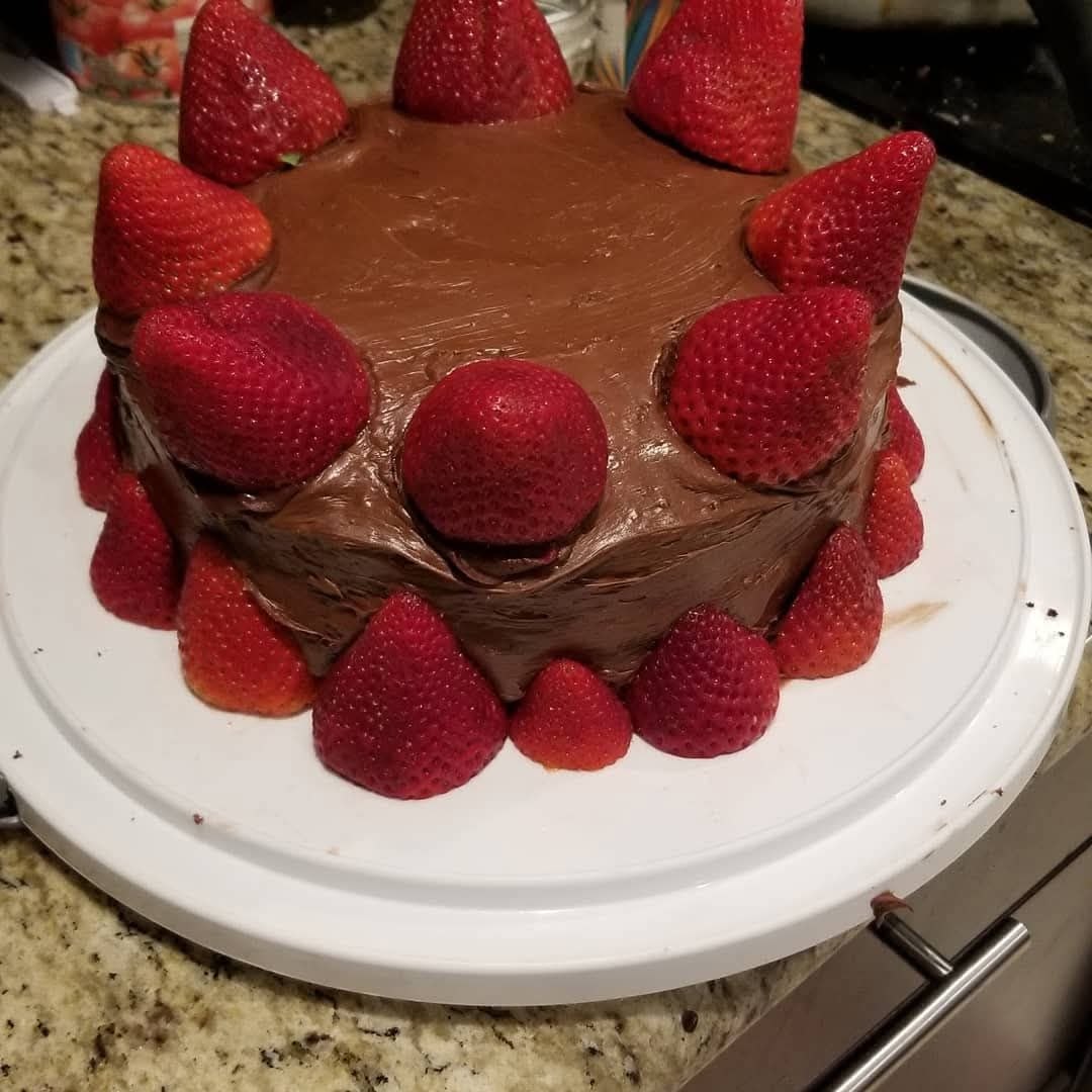 Chocolate-frosted cake studded with whole strawberries
