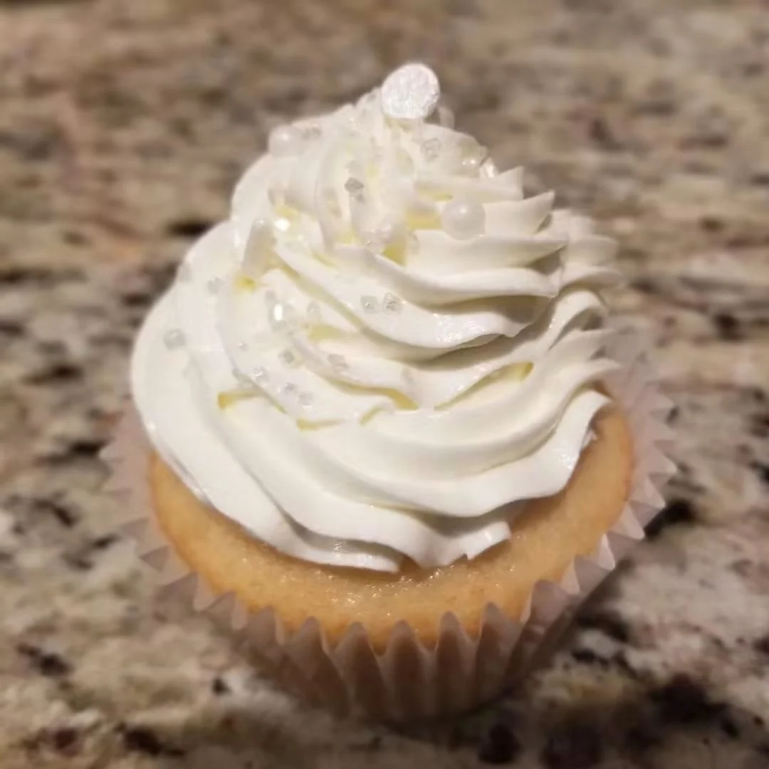 Cupcake with a tall white frosting swirl and pearl-like decorations